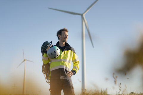 Techniker auf einem Feld in einem Windpark mit Kletterausrüstung, lizenzfreies Stockfoto