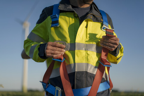 Close-up of technician at a wind farm putting on climbing harness stock photo