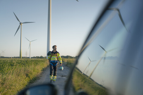 Techniker auf einem Feldweg in einem Windpark mit Kletterausrüstung, lizenzfreies Stockfoto