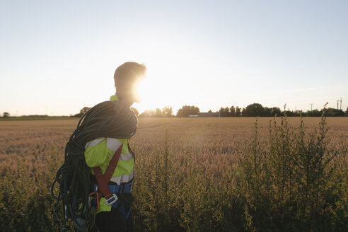 Techniker mit Kletterausrüstung auf einem Feld bei Sonnenuntergang - GUSF01374