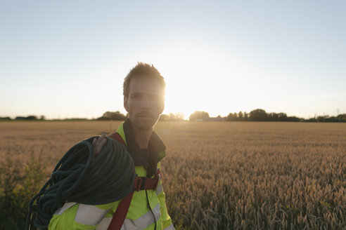 Techniker mit Kletterausrüstung auf einem Feld bei Sonnenuntergang - GUSF01375