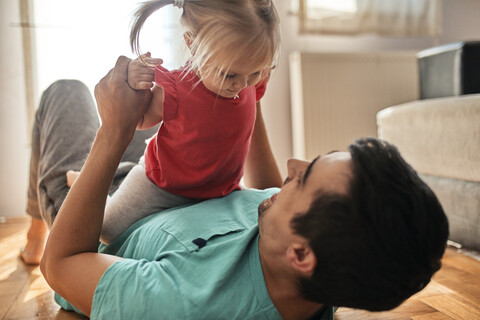 Kleines Mädchen spielt mit ihrem Vater zu Hause, lizenzfreies Stockfoto