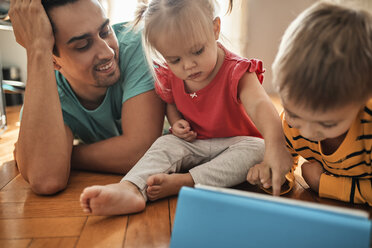 Father and his children using digital tablet at home - ZEDF01772