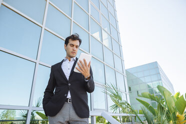 Businessman using tablet outside office building - KIJF02094