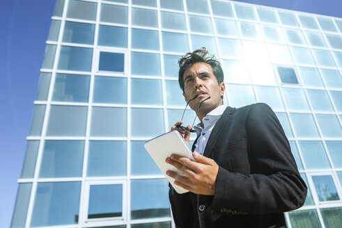 Geschäftsmann mit Tablet und Sonnenbrille vor einem Bürogebäude - KIJF02102