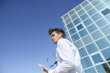 Businessman with tablet and sunglasses outside office building - KIJF02103