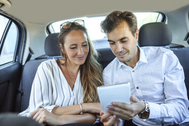 Pärchen benutzt Tablet auf dem Rücksitz eines Autos - KIJF02104