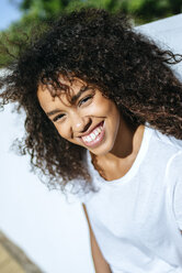 Porträt einer lachenden jungen Frau mit lockigem Haar - KIJF02117
