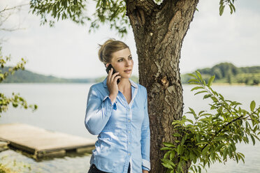 Woman on cell phone at a lake - MOEF01483