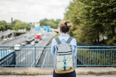 Rückansicht einer Frau mit Rucksack auf einer Autobahnbrücke - MOEF01535
