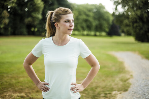 Sportliche junge Frau, die in einem Park steht und zur Seite schaut, lizenzfreies Stockfoto