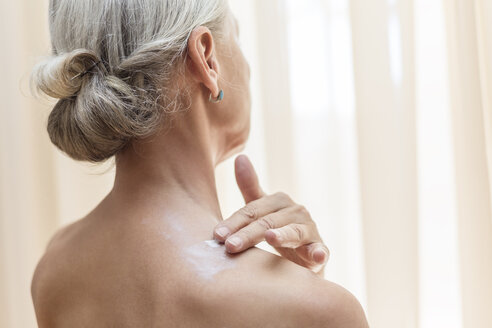 Back view of senior woman applying cream on neck - VGF00106