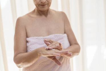 Senior woman applying cream on hand in the morning - VGF00107