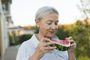 Porträt einer älteren Frau, die im Garten eine Scheibe Wassermelone isst - VGF00132