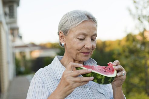 Portrait of senior woman eating watermelon slice in the garden - VGF00132