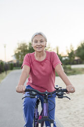 Porträt einer lächelnden älteren Frau beim Fahrradfahren - VGF00140