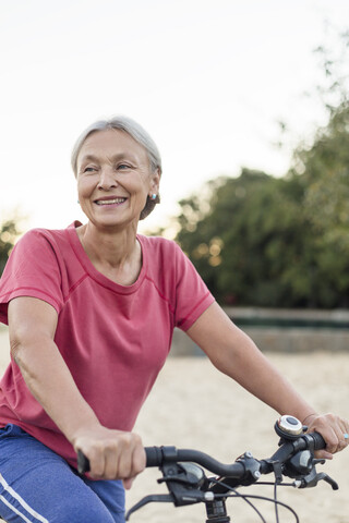 Porträt einer lächelnden älteren Frau beim Fahrradfahren, lizenzfreies Stockfoto