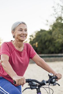 Porträt einer lächelnden älteren Frau beim Fahrradfahren - VGF00143