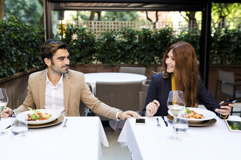 Lächelnde Frau und Mann mit Mobiltelefon in einem Restaurant - VABF01667
