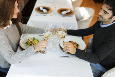 Lächelndes Paar stößt in einem Restaurant mit Weingläsern an - VABF01690