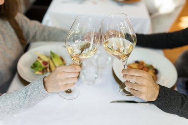 Close-up of couple clinking wine glasses in a restaurant - VABF01692