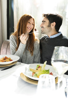 Lächelnde Frau lässt Mann das Essen in einem Restaurant kosten - VABF01703