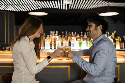 Lächelndes Paar stößt in einer Bar auf Biergläser an - VABF01705