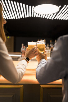 Nahaufnahme eines Paares, das in einer Bar mit Biergläsern anstößt - VABF01707