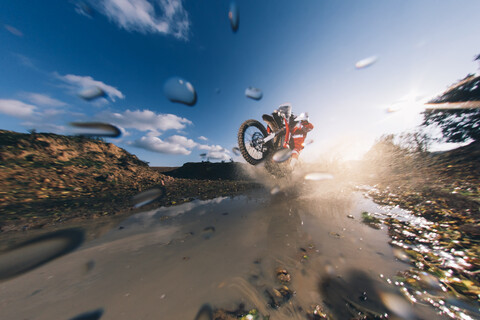 Motocross-Fahrer fährt durch das Wasser und spritzt, lizenzfreies Stockfoto