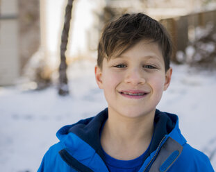 Porträt eines lächelnden Jungen mit Zahnspange und warmer Kleidung im Winter - CAVF54091