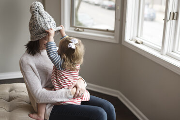 Mutter mit Tochter auf dem Bett sitzend zu Hause - CAVF54118