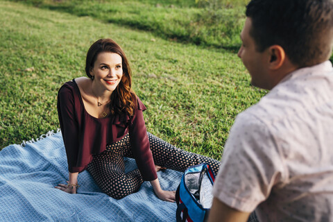 High angle view of smiling couple relaxing on blanket at park stock photo