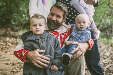 Porträt eines Mannes und von Kindern gegenüber einer Familie auf einem Feld im Park - CAVF54151