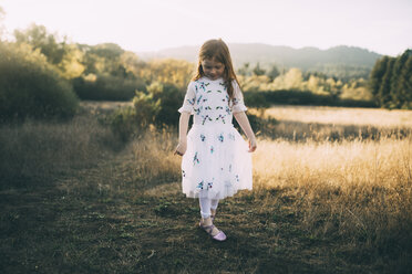 Full length of girl wearing white dress while playing at park - CAVF54156