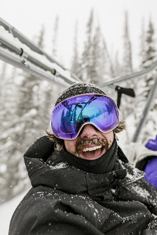 Fröhlicher Mann mit Skibrille im Winter, lizenzfreies Stockfoto