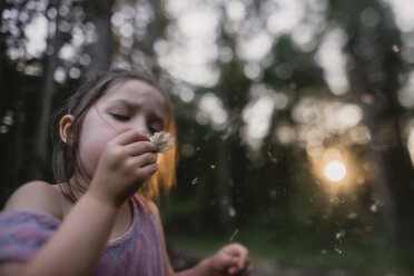 Playful girl blowing dandelion on field - CAVF54217