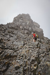 Low angle view of sporty hiker climbing mountain against sky - CAVF54262