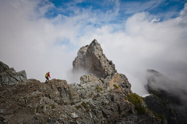 Hohe Winkel Ansicht von Wanderer mit Rucksack auf Berg inmitten von Wolken - CAVF54263