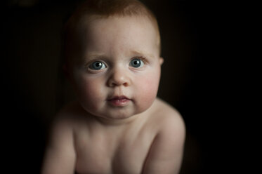 Close-up portrait of cute shirtless baby boy in darkroom - CAVF54277