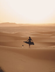 Rückansicht einer mit einer Laterne tanzenden Frau in der Sahara-Wüste gegen den Himmel bei Sonnenuntergang - CAVF54290