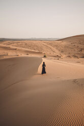 Rückansicht einer Frau, die in der Sahara-Wüste gegen den klaren Himmel bei Sonnenuntergang läuft - CAVF54293