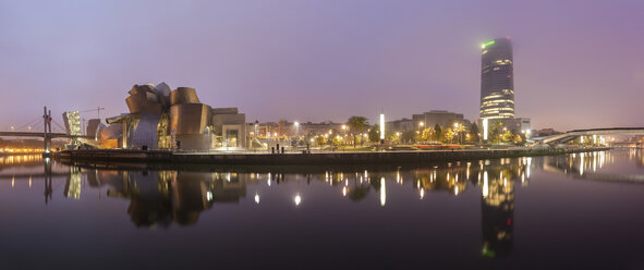 Panoramablick auf beleuchtete Gebäude in der Stadt am Fluss gegen den Himmel in der Abenddämmerung - CAVF54295