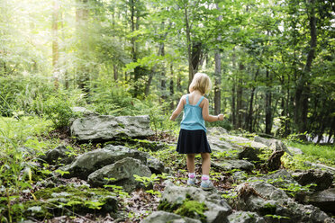 Rückansicht eines Mädchens, das auf einem Feld im Wald steht - CAVF54301