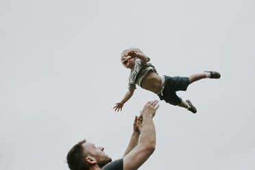 Verspielter Vater wirft Sohn in die Luft gegen den klaren Himmel - CAVF54313