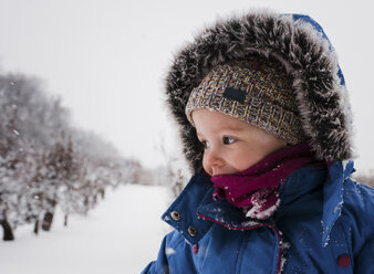 Girl in warm clothing standing on snow covered field against sky - CAVF54397