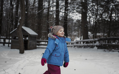 Girl walking on snow covered field in forest - CAVF54402