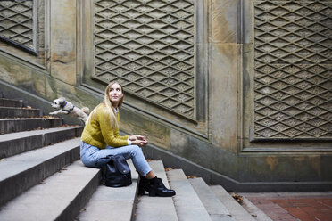 Side view of woman looking away while sitting on steps at park - CAVF54471