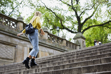 Low angle view of woman climbing steps at park - CAVF54475