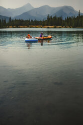 Brüder beim Rafting auf dem See gegen die Berge - CAVF54505