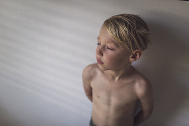 High angle view of shirtless boy standing by wall at home - CAVF54506